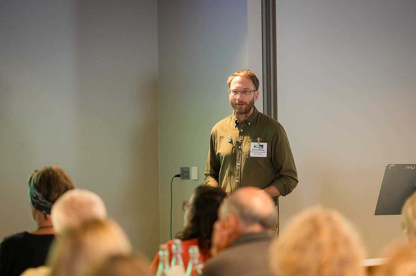Bruce Winney speaks at the Big Chalk Conference, highlighting the importance of chalk landscapes and the need for collaboration in their preservation. Attendees listen attentively to his expert insights.