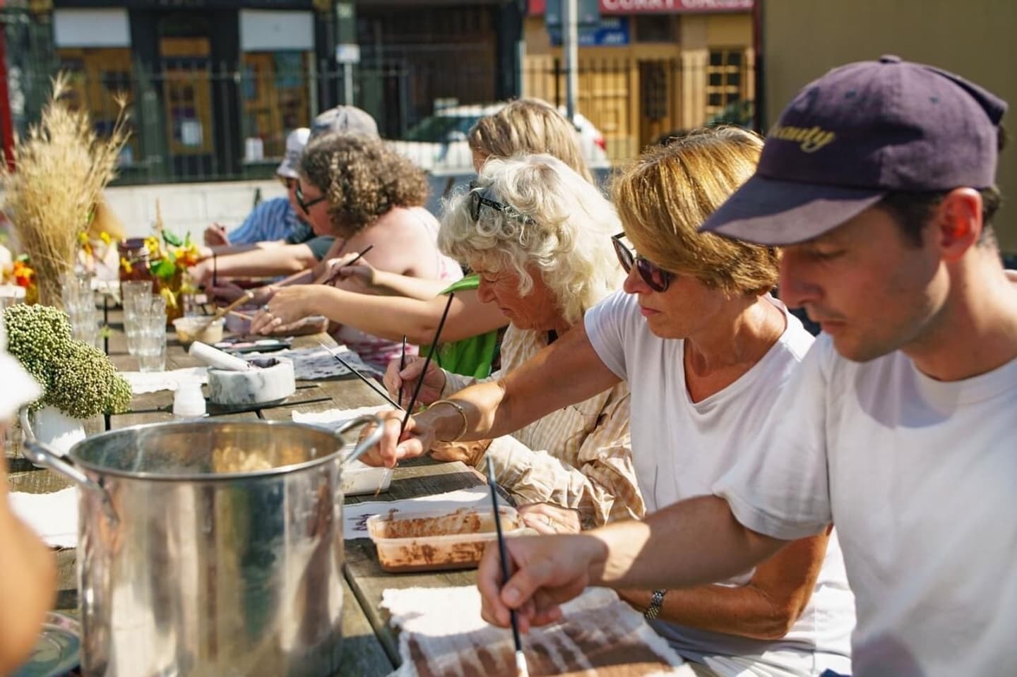 Participants at a natural dyes workshop, mixing colours and dyeing fabric using eco-friendly techniques, surrounded by bowls of vibrant dyes and plants